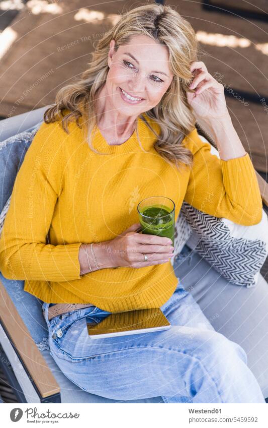 Portrait of smiling mature woman sitting on terrace with digital tablet and green smoothie human human being human beings humans person persons