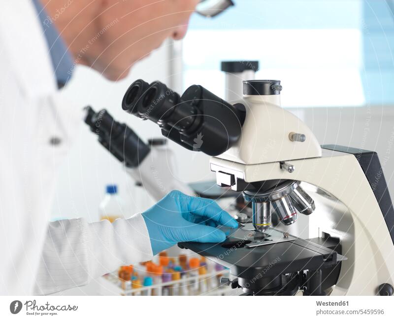 Medical Screening, Scientist examining a glass slide containing a human sample under a microscope and blood sample Occupation Work job jobs profession
