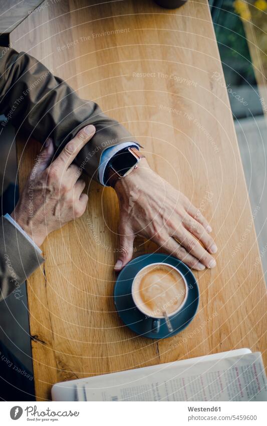 Mature businessman sitting in coffee shop, checking time Coffee smartwatch smart watch Seated drinking cafe Drink beverages Drinks Beverage food and drink