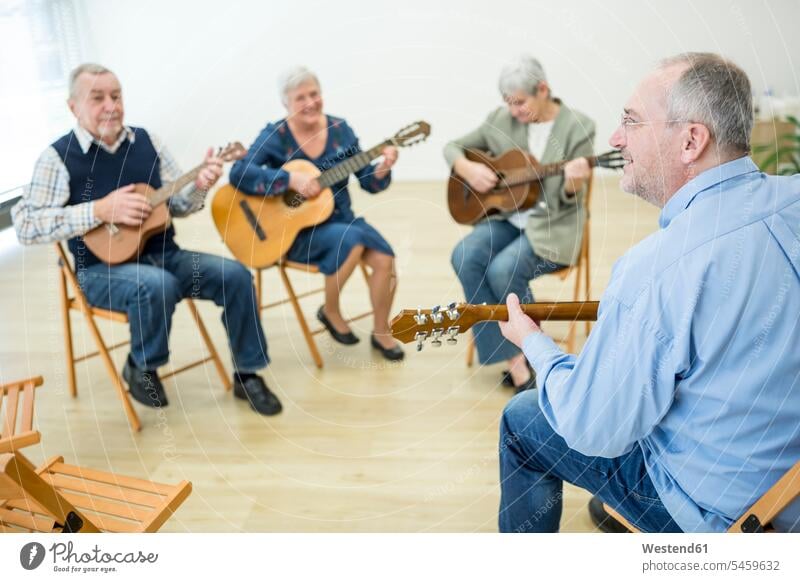 Seniors in retirement home attending guitar class, making music human human being human beings humans person persons caucasian appearance caucasian ethnicity