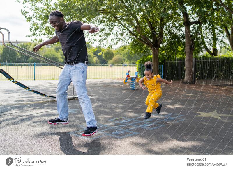 Father and daughter playing hopscotch on a playground relax relaxing smile jumps Leaping seasons summer time summertime summery delight enjoyment Pleasant