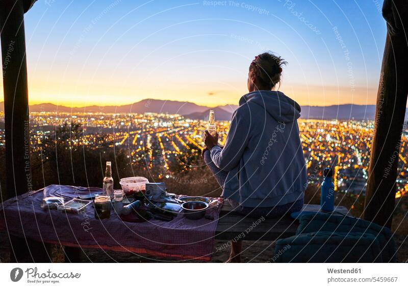 Chile, Santiago, woman drinking a beer in the mountains above the city at sunset town cities towns sunsets sundown Beer Beers Ale outdoors outdoor shots