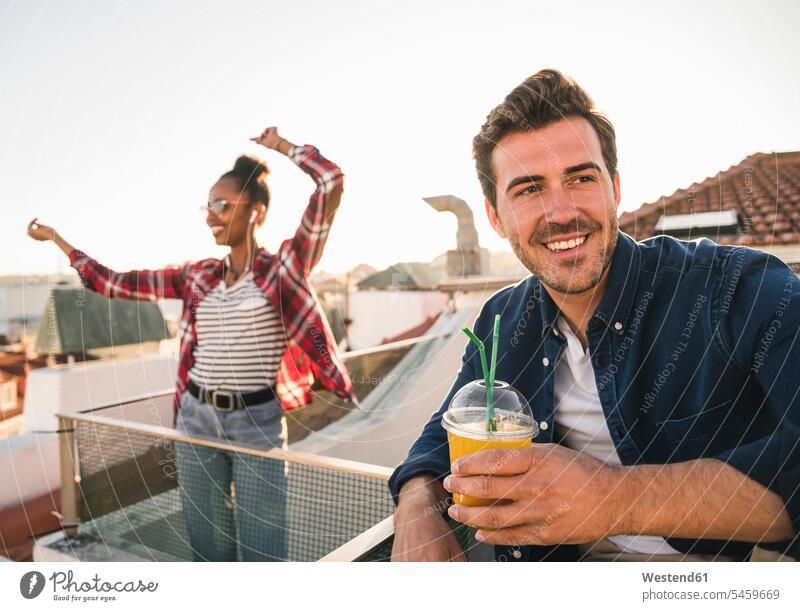 Happy young couple having a rooftop party human human being human beings humans person persons African black black ethnicity coloured caucasian appearance