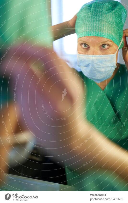 Woman in scrubs looking in mirror putting on mask health Selective focus Differential Focus expertise expert knowledge know-how analytic expertise know how
