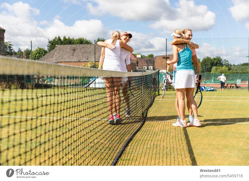 Mature women finishing tennis match on grass court hugging human human being human beings humans person persons caucasian appearance caucasian ethnicity