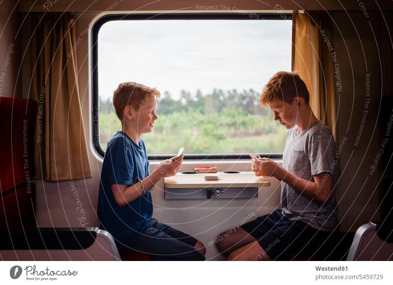 Side view of boys playing cards while traveling in train, Thailand, Asia color image colour image day daylight shot daylight shots day shots daytime