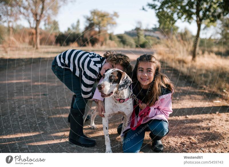 Smiling girl and boy with dog on roadside color image colour image outdoors location shots outdoor shot outdoor shots Spain 6-7 years 6 to 7 years children kid