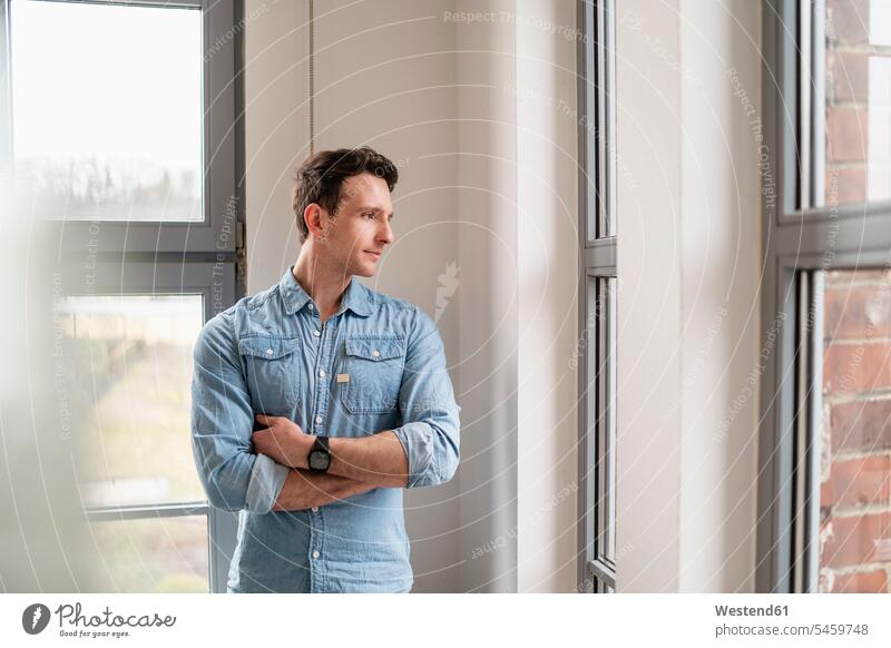 Businessman looking out of window in office offices office room office rooms Business man Businessmen Business men windows view seeing viewing workplace