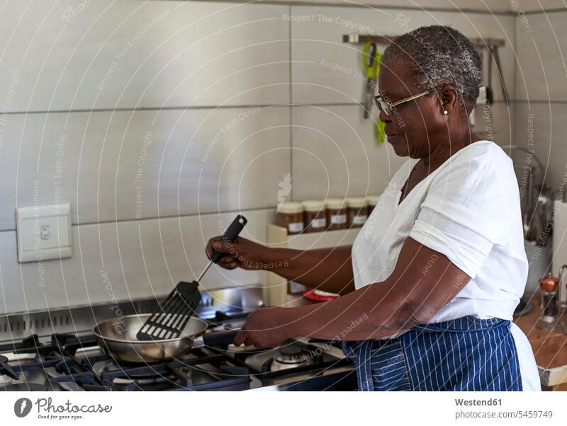 Senior woman cooking at gas stove in kitchen human human being human beings humans person persons African black black ethnicity coloured 1 one person only