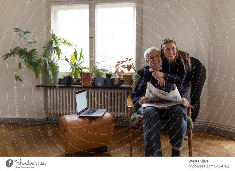 Portrait of happy young woman and senior man with newspaper at home human human being human beings humans person persons caucasian appearance