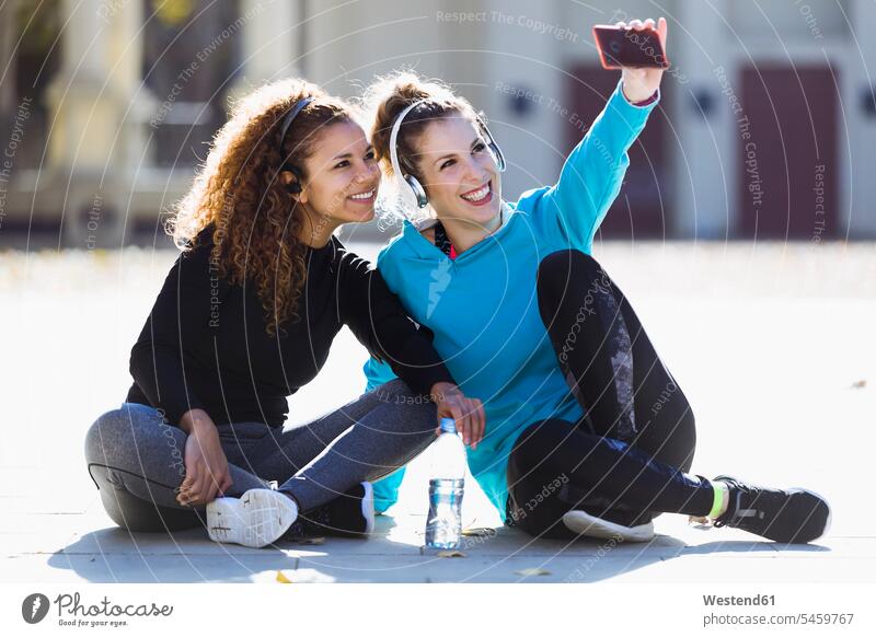 Two smiling sportive young women having a break taking a selfie female friends sporting sporty athletic Selfie Selfies smile woman females mate friendship