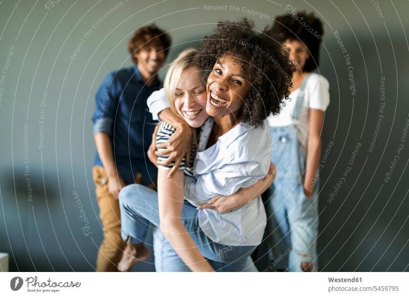 Two happy women hugging with friends in background embracing embrace Embracement cheerful gaiety Joyous glad Cheerfulness exhilaration merry gay portrait