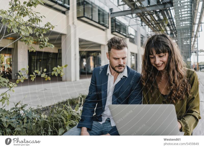 Businessman and casual businesswoman using laptop outdoors human human being human beings humans person persons caucasian appearance caucasian ethnicity