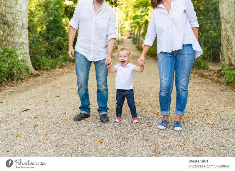 Happy girl walking hand in hand with parents in a park human human being human beings humans person persons caucasian appearance caucasian ethnicity european