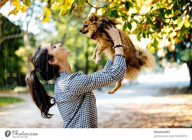 Happy young woman holding dog in a park animals creature creatures domestic animal pet Canine dogs relax relaxing smile delight enjoyment Pleasant pleasure