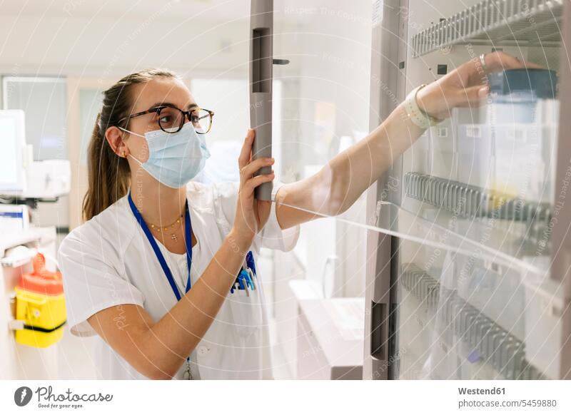 Female doctor taking medicines from cabinet in pharmacy at hospital color image colour image Spain indoors indoor shot indoor shots interior interior view