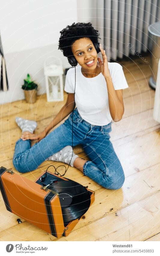 Young woman sitting on grounf listening music from record player, using headphones turntable young women young woman sitting on ground Sitting On The Floor