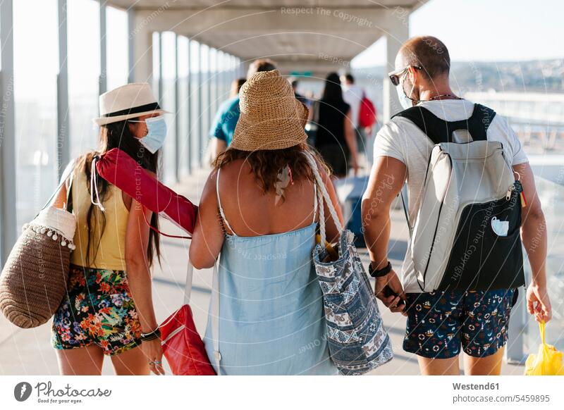 Friends wearing masks walking on gangway at harbor color image colour image Spain leisure activity leisure activities free time leisure time casual clothing