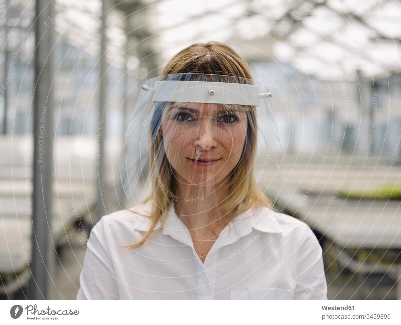 Close-up of confident businesswoman wearing face shield in greenhouse color image colour image Germany business people businesspeople Business Professional