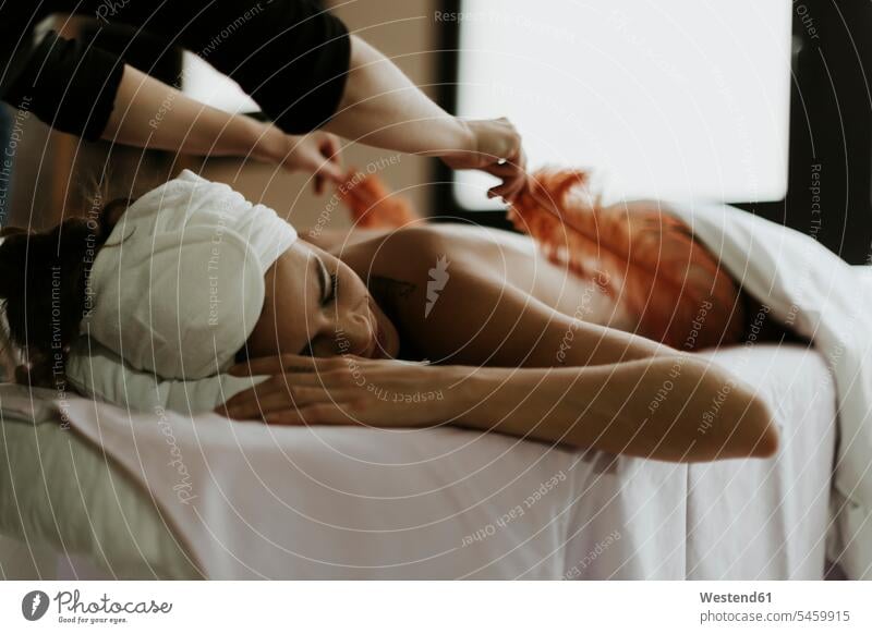 Young woman receiving a massage with feathers in a spa massage therapy females women receive treatment Medical Treatment treatments Adults grown-ups grownups