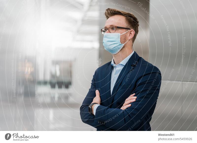 Businessman with arms crossed wearing mask in city color image colour image outdoors location shots outdoor shot outdoor shots day daylight shot daylight shots