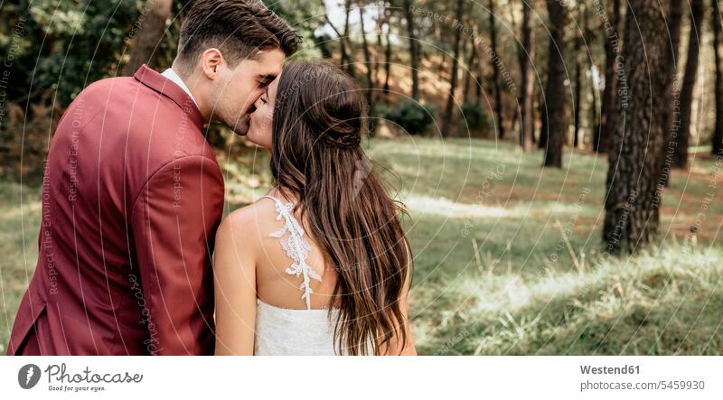 Back view of bride and groom kissing in forest woods forests Wedding getting married marrying Marriage kisses brides bridegrooms bridal couple bridal couples