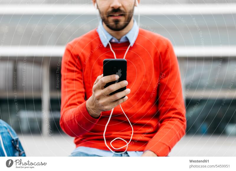 Casual businessman sitting on a bench in the city, using his smartohone and earphones urban urbanity ear phone ear phones Smartphone iPhone Smartphones casual
