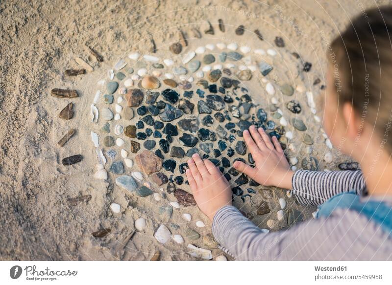 Little girl making a heart from seashells on the beach playing beaches females girls sand sandy child children kid kids people persons human being humans