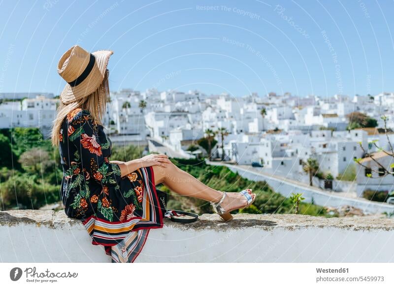 Spain, Cadiz, Vejer de la Frontera, fashionable woman sitting on balustrade looking at view parapet View Vista Look-Out outlook seeing viewing Seated females