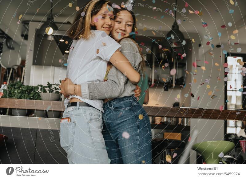 Loving teenage friends embracing while standing in birthday party at home color image colour image Germany indoors indoor shot indoor shots interior