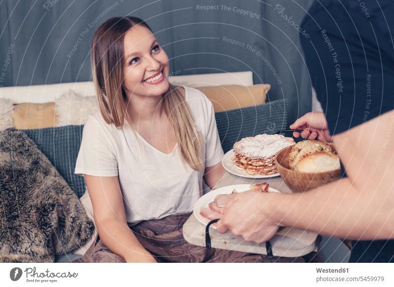 Young man serving breakfast in bed for girlfriend couple twosomes partnership couples beds Breakfast relaxed relaxation people persons human being humans