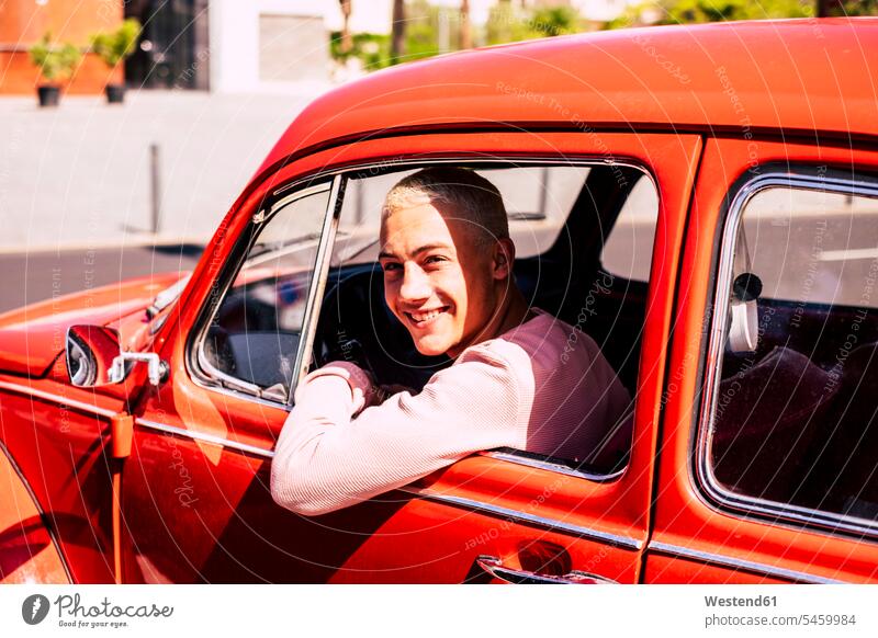 Portrait of happy teenage boy sitting in vintage car looking out of window human human being human beings humans person persons caucasian appearance