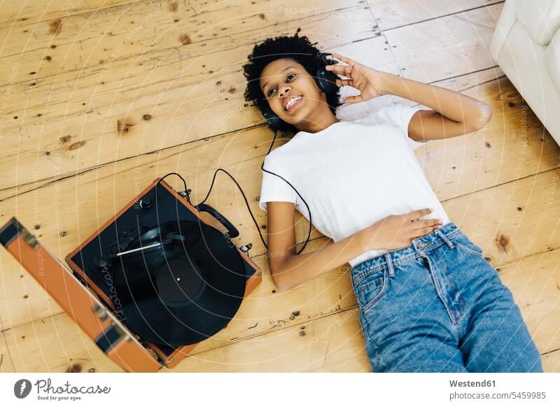 Young woman at home listening vinyl records, lying on ground Listening Music record player turntable headphones headset young women young woman analogue Media