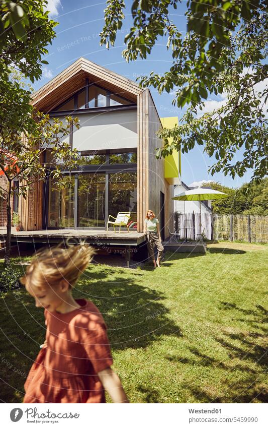 Mother with daughter standing on grassy land in yard outside tiny house color image colour image Germany leisure activity leisure activities free time