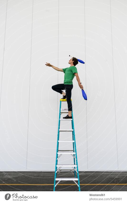 Acrobat standing on ladder, juggling - a Royalty Free Stock Photo