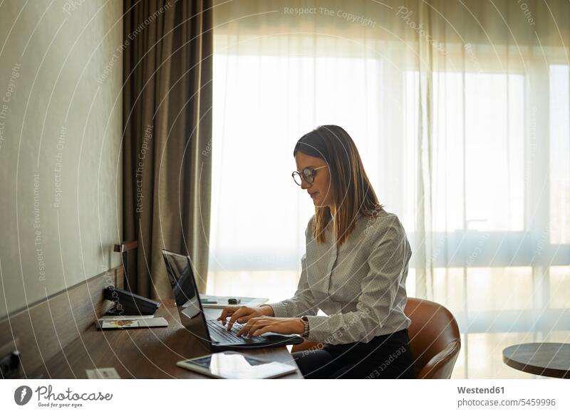 Businesswoman sitting at desk in hotel room using laptop Occupation Work job jobs profession professional occupation business life business world
