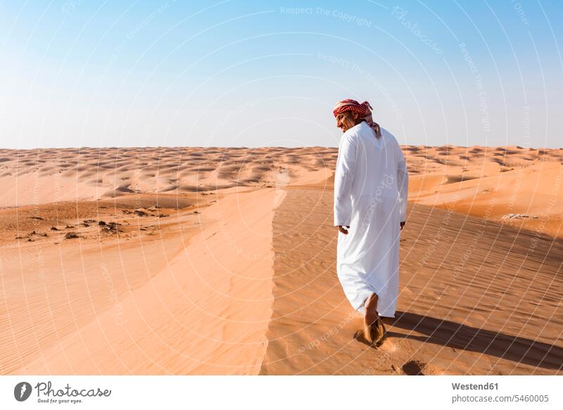 Bedouin walking in the desert, Wahiba Sands, oman headscarf head scarf head scarves Head Scarf head cloths headscarves clear sky cloudless vastness wide Broad
