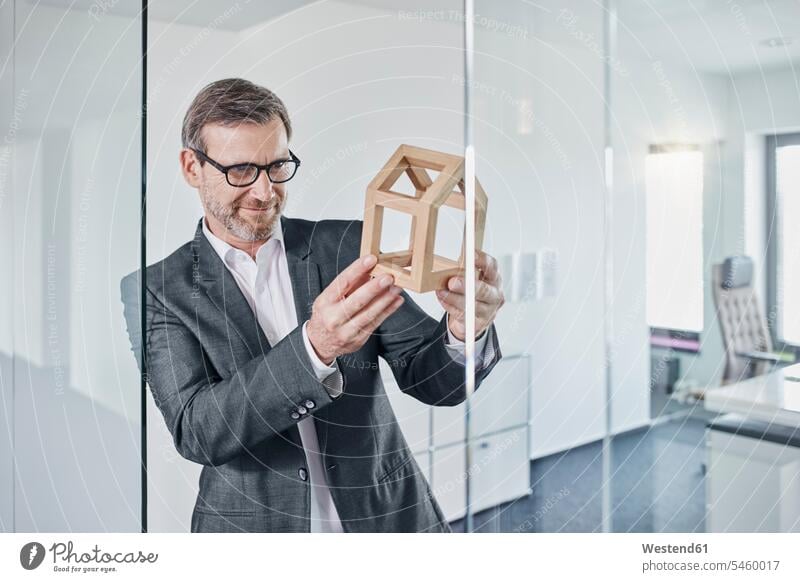Smiling businessman looking at architectural model in office smiling smile eyeing offices office room office rooms holding Architectural Model Businessman