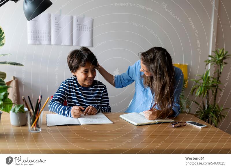Female tutor talking with smiling boy while sitting at table color image colour image Spain casual clothing casual wear leisure wear casual clothes
