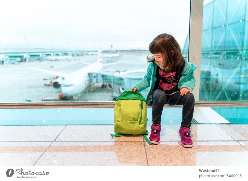 Girl with backpack sitting at the airport in front of a plane human human being human beings humans person persons caucasian appearance caucasian ethnicity