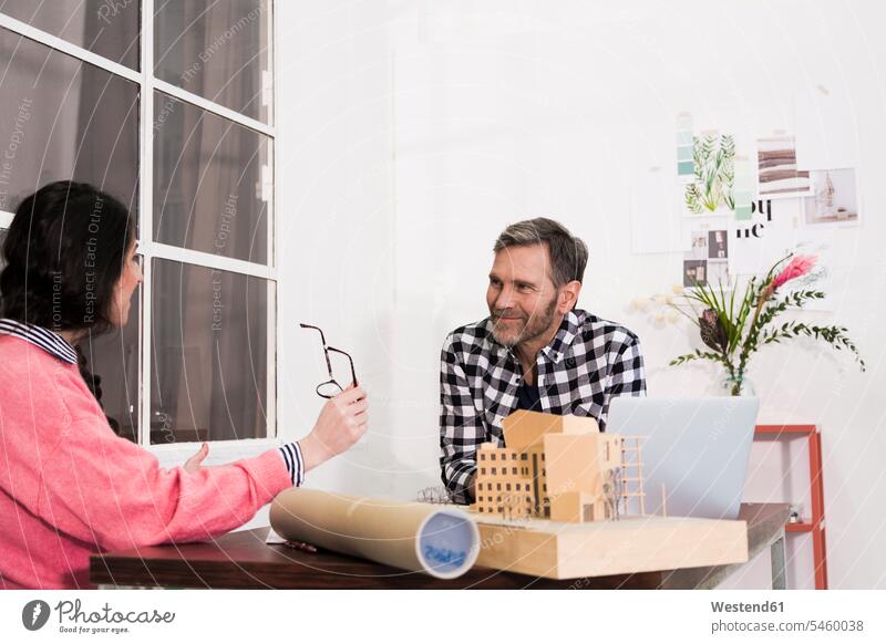 Smiling colleagues sitting at table in an architect's office offices office room office rooms smiling smile Seated Table Tables workplace work place