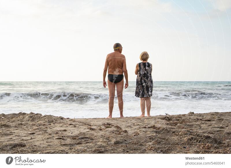 Italy, Sicily, senior couple at the beach looking at the sea twosomes partnership couples vacation Holidays water rear view back view view from the back wave