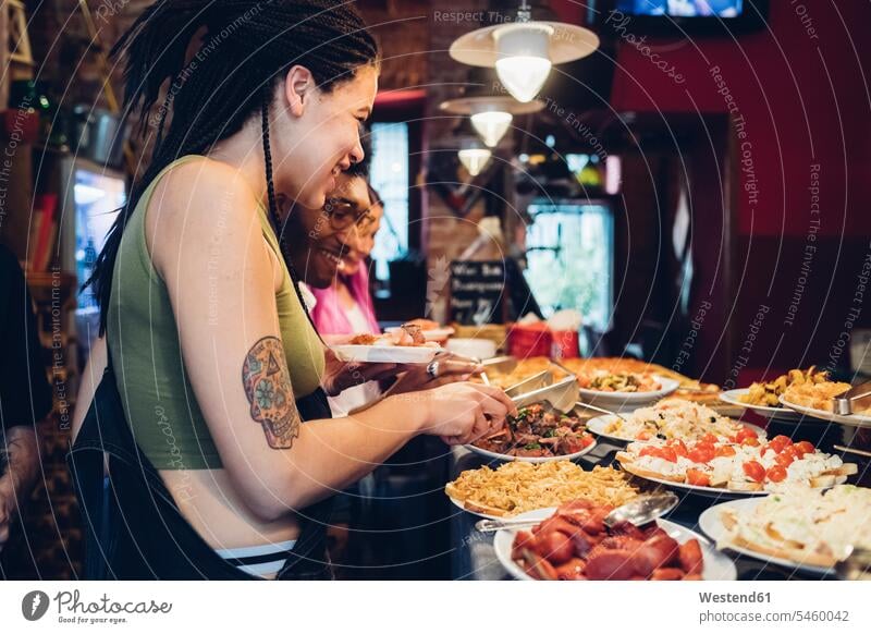Happy friends taking food from buffet in a restaurant human human being human beings humans person persons caucasian appearance caucasian ethnicity european