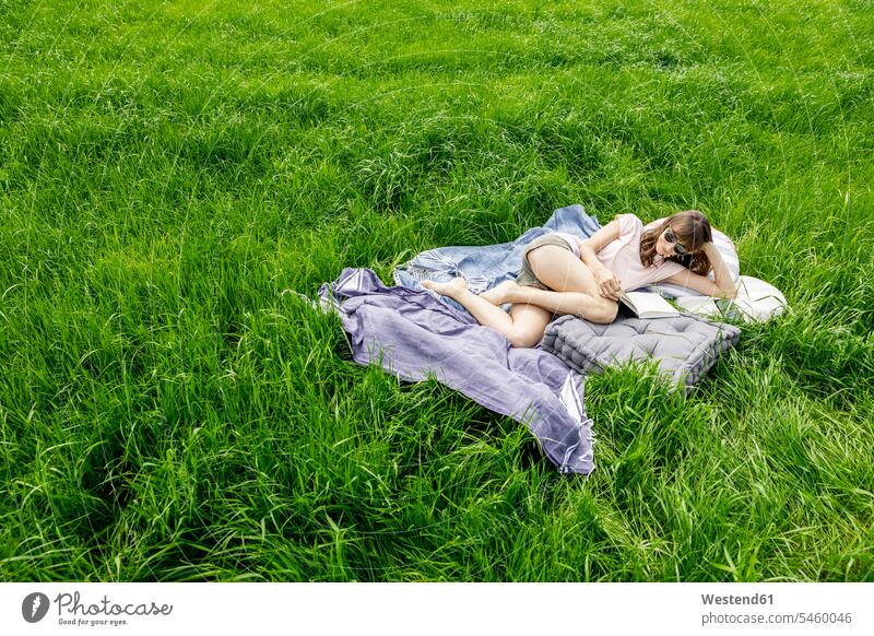 Relaxed woman lying on a meadow reading a book human human being human beings humans person persons caucasian appearance caucasian ethnicity european 1