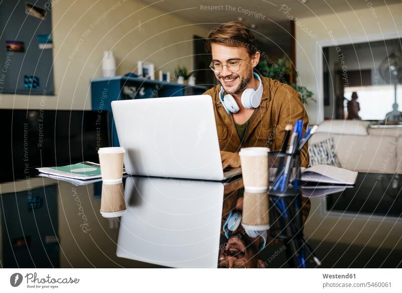 Smiling man working on table at home using laptop Occupation Work job jobs profession professional occupation business life business world business person