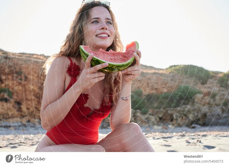 Happy young woman holding watermelon slice on the beach swim wear bathing costume bathing costumes bathing suit bathing suits Swimming Costume Swimming Suit