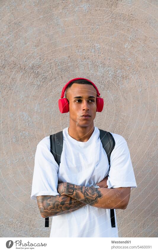 Portrait of tattooed young man listening music with wireless red headphones human human being human beings humans person persons Mixed Race mixed race ethnicity
