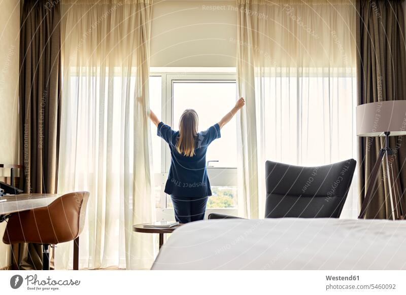 Chambermaid opening curtains of window in hotel room color image colour image indoors indoor shot indoor shots interior interior view Interiors Millennials