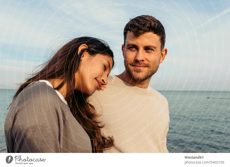 Young woman leaning on man's shoulder against sky at beach color image colour image outdoors location shots outdoor shot outdoor shots day daylight shot