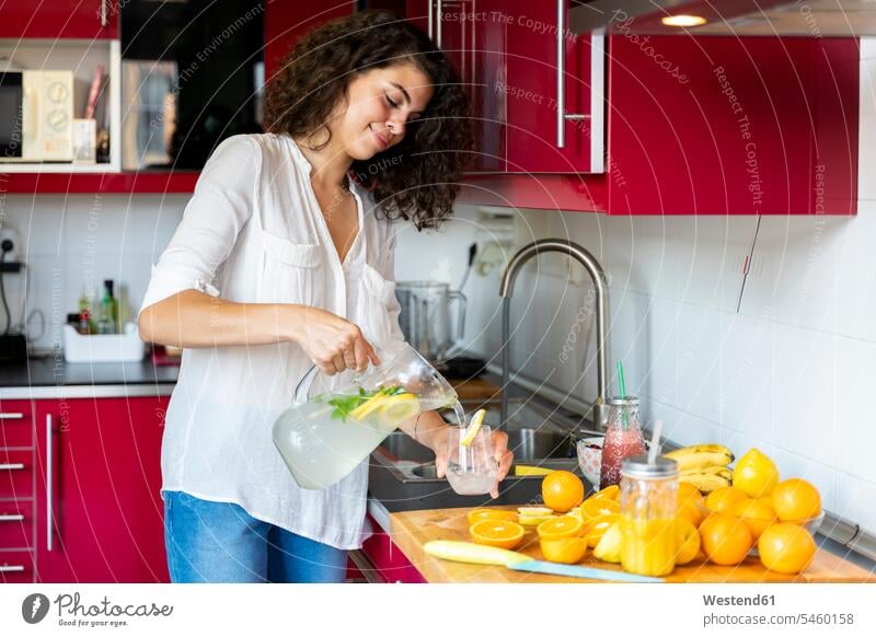 Young woman in kitchen at home pouring lemonade into glass human human being human beings humans person persons caucasian appearance caucasian ethnicity